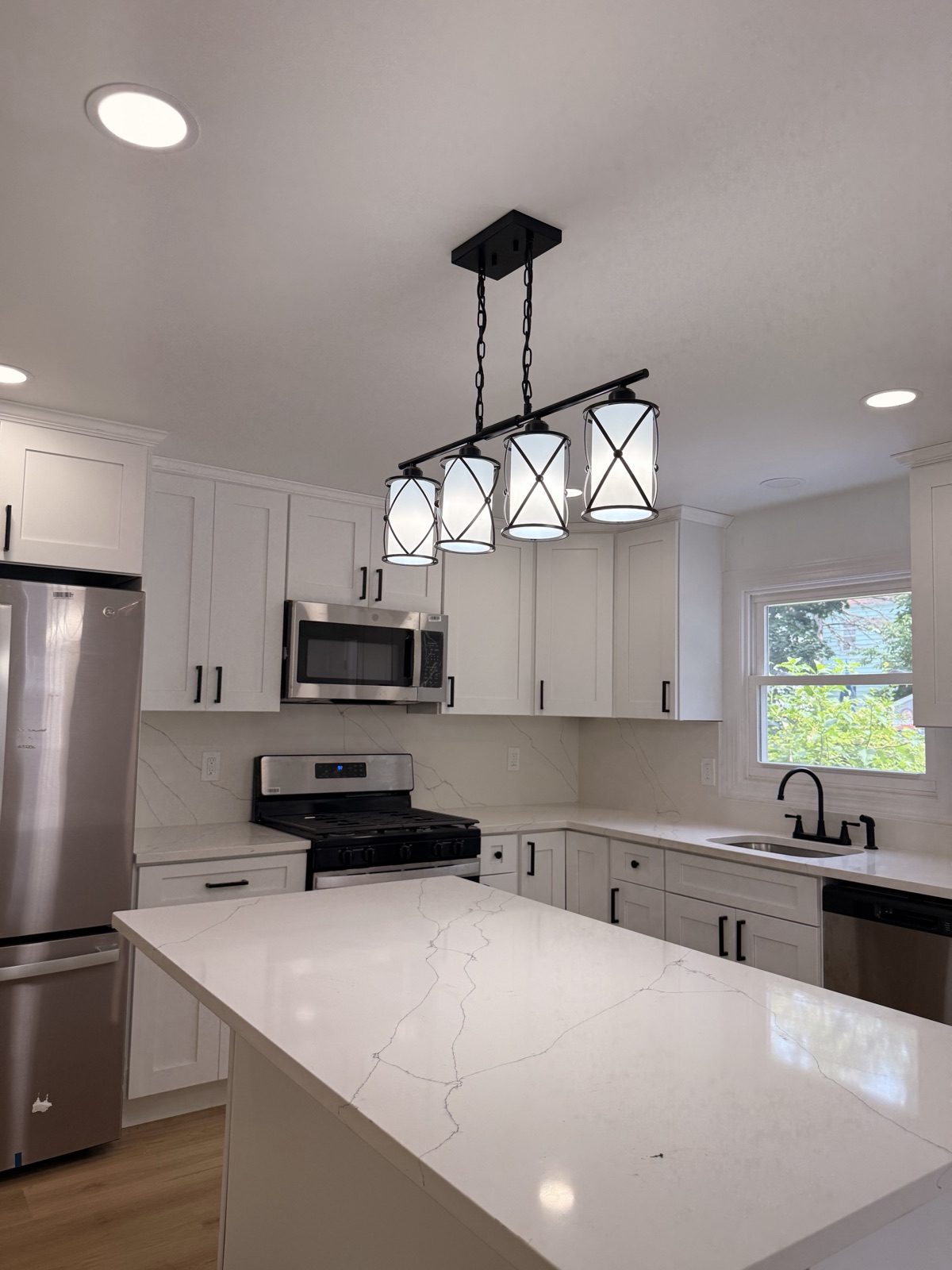 Kitchen with waterfall quartz island and lantern-style pendant lighting